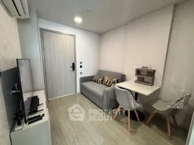 Modern compact living room with sofa, TV, and dining area in a stylish apartment.