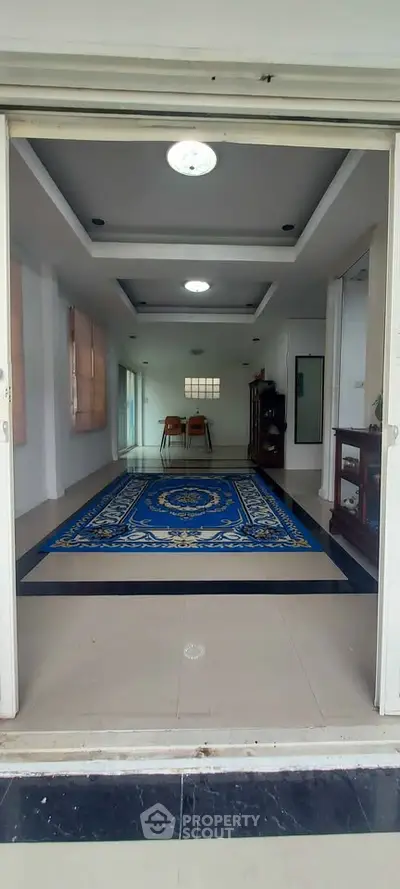Spacious interior with elegant blue rug and modern ceiling lights, perfect for versatile living space.