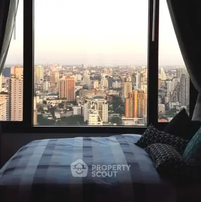 Stunning cityscape view from a cozy bedroom window in a high-rise apartment.