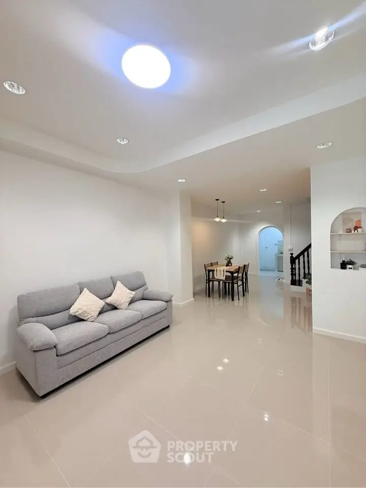 Spacious modern living room with elegant dining area and stylish staircase.