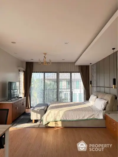 Spacious bedroom with large windows, ample natural light, and elegant decor featuring a comfortable bed, wooden furniture, and a cozy seating area.