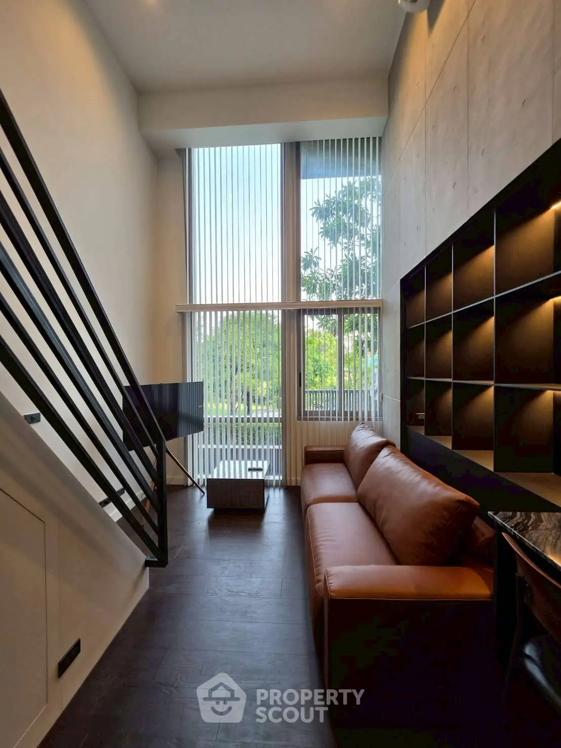 Modern living room with high ceilings, large windows, and stylish leather sofa in a contemporary loft apartment.