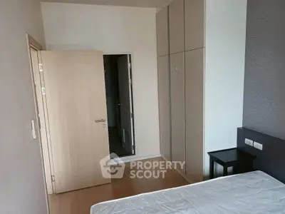 Minimalist bedroom with wooden flooring and built-in wardrobe