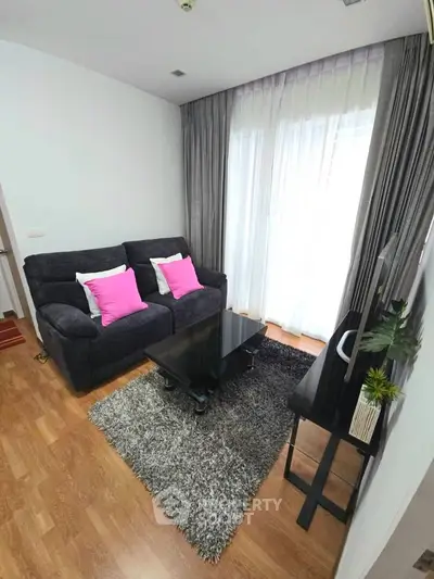 Cozy living room with plush sofa, stylish decor, and natural light through large windows.