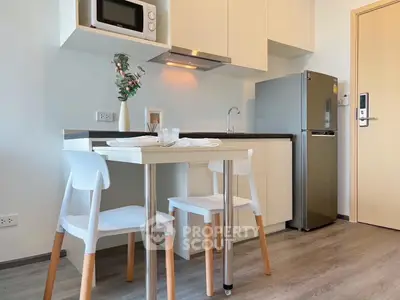 Modern compact kitchen with dining area, featuring sleek cabinetry and stainless steel appliances.