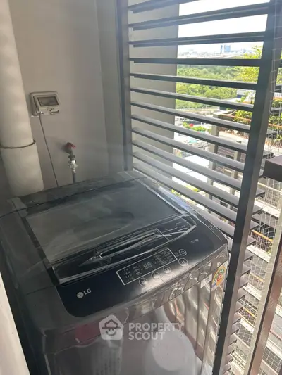 Compact balcony with washing machine and city view, perfect for urban living convenience.