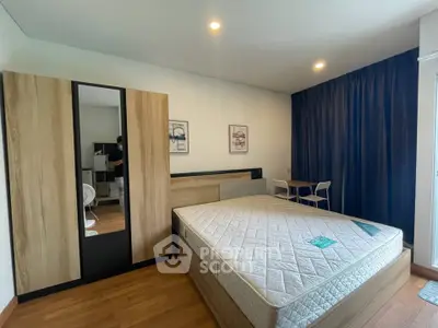 Spacious bedroom with modern furniture and large window, perfect for comfort and relaxation.