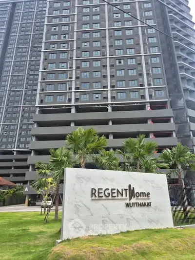 Modern high-rise building with lush landscaping at Regent Home Wuttakat.