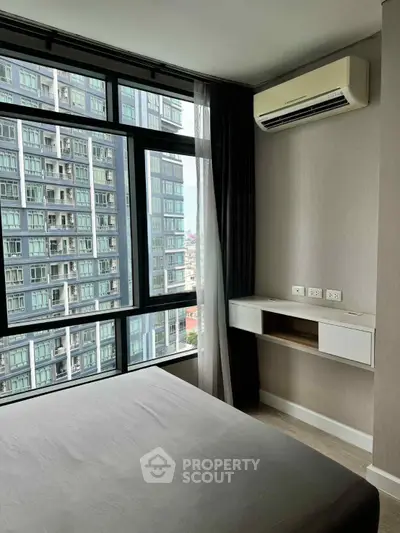 Modern bedroom with large windows offering city views in a high-rise building.