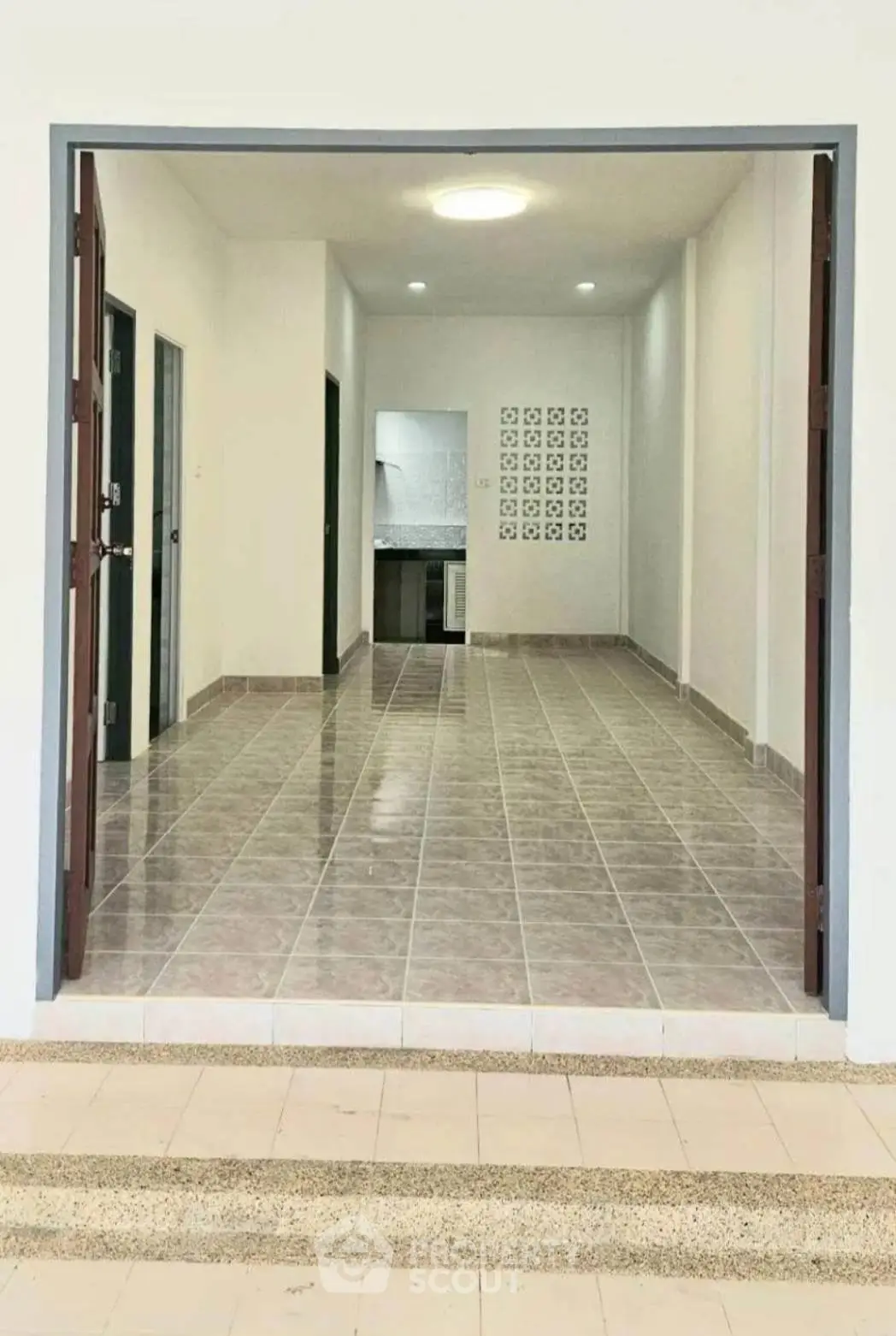 Spacious open-plan living area with tiled flooring and modern kitchen view.