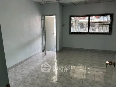Spacious empty room with tiled floor and large window, ideal for customization.