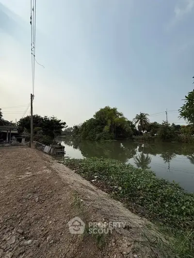 Serene riverside view with lush greenery and clear sky, perfect for tranquil living.