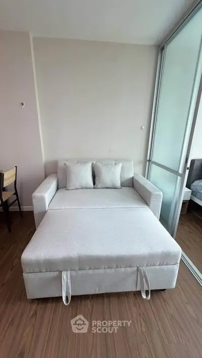 Modern living room with stylish pull-out sofa bed and wooden flooring, perfect for cozy urban living.