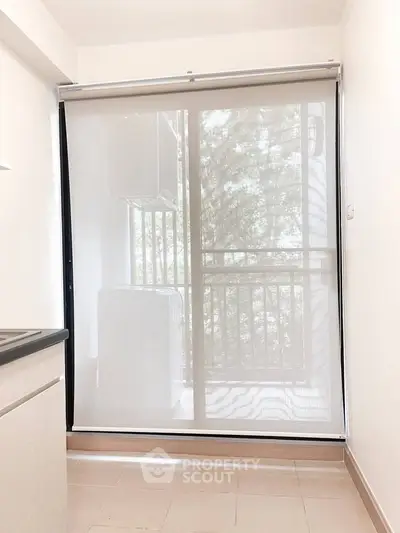 Bright kitchen with large window and balcony view, featuring modern roller blinds.