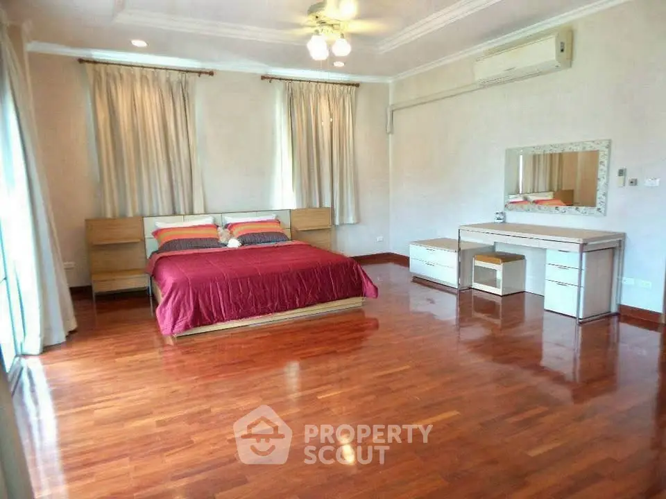 Spacious bedroom with polished wood floors and elegant furnishings