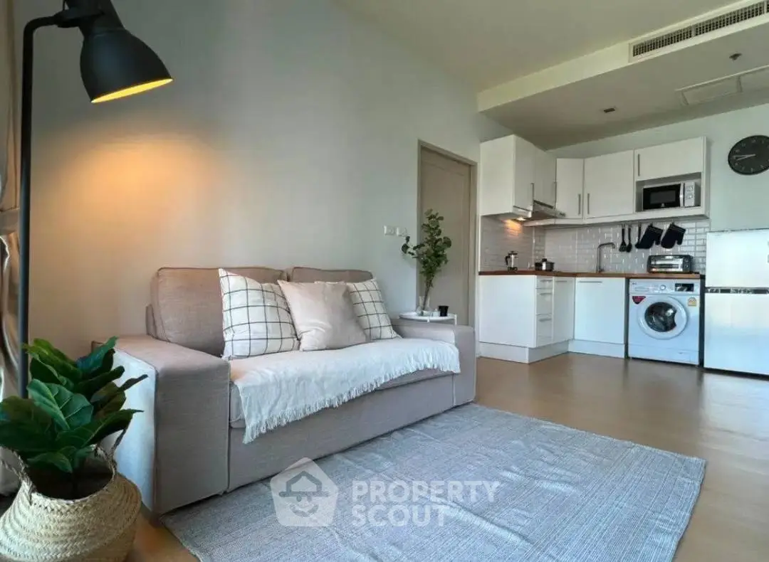Modern open-layout living room with cozy sofa and stylish kitchen appliances.