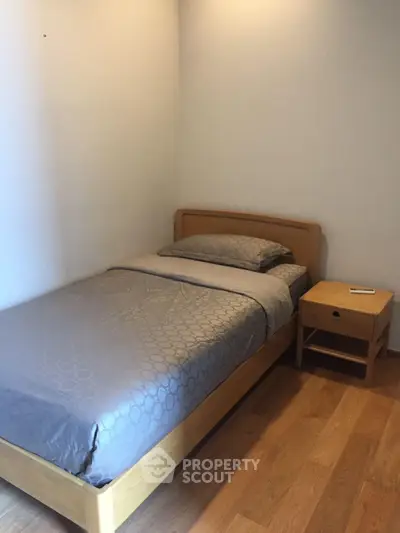 Cozy single bedroom with wooden flooring and minimalist design, perfect for a peaceful retreat.