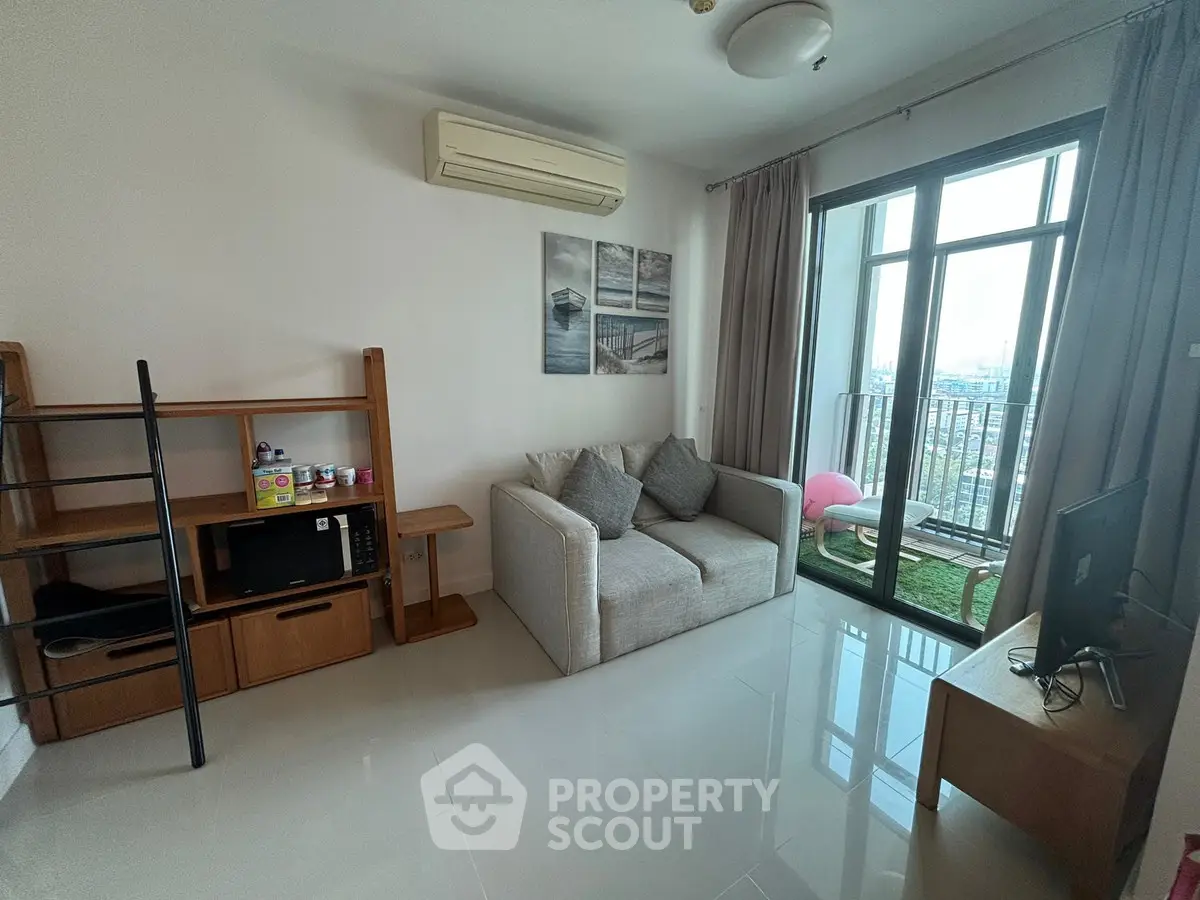 Modern living room with balcony view, featuring cozy sofa and sleek TV setup.
