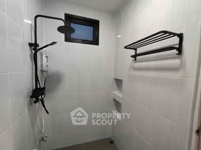 Modern bathroom with sleek shower fixtures and towel rack, featuring minimalist design and neutral tiles.