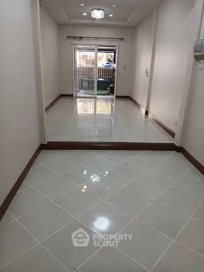 Spacious tiled room with sliding glass doors leading to a balcony, perfect for natural light and outdoor access.