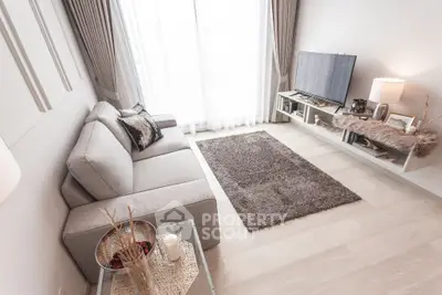 Modern living room with cozy sofa and large TV, bright natural light