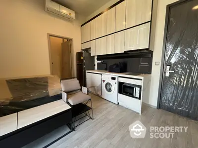 Compact modern studio apartment with integrated appliances, sleek cabinetry, and a comfortable living space, perfect for urban living.