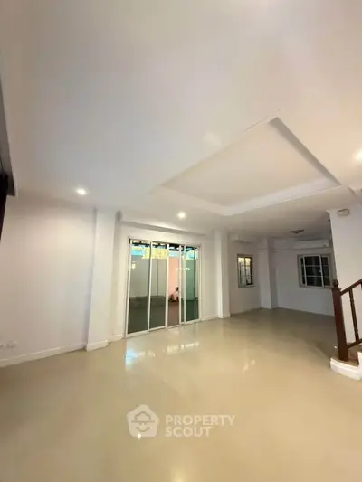 Spacious living room with modern ceiling design and sliding glass doors.