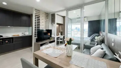 Modern open-plan apartment with sleek kitchen and cozy living area, featuring a bright bedroom and city view.