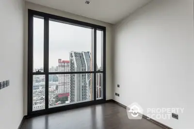 Spacious high-rise apartment with large windows offering a panoramic city view, sleek dark flooring, and ample natural light.