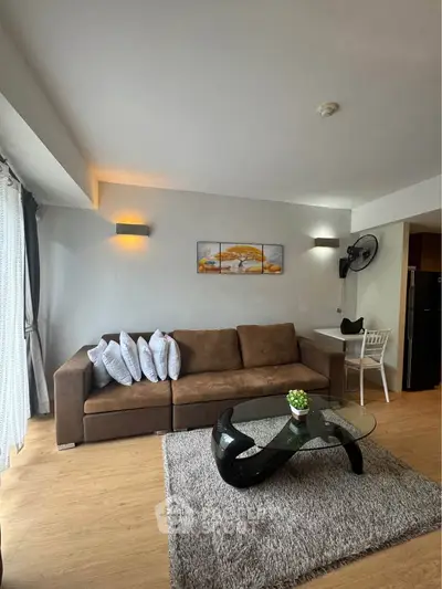 Stylish living room with modern decor, cozy brown sofa, and elegant glass coffee table in a bright apartment.