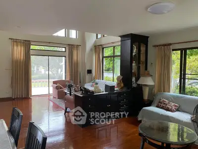 Spacious living room with elegant decor and large windows offering garden views.