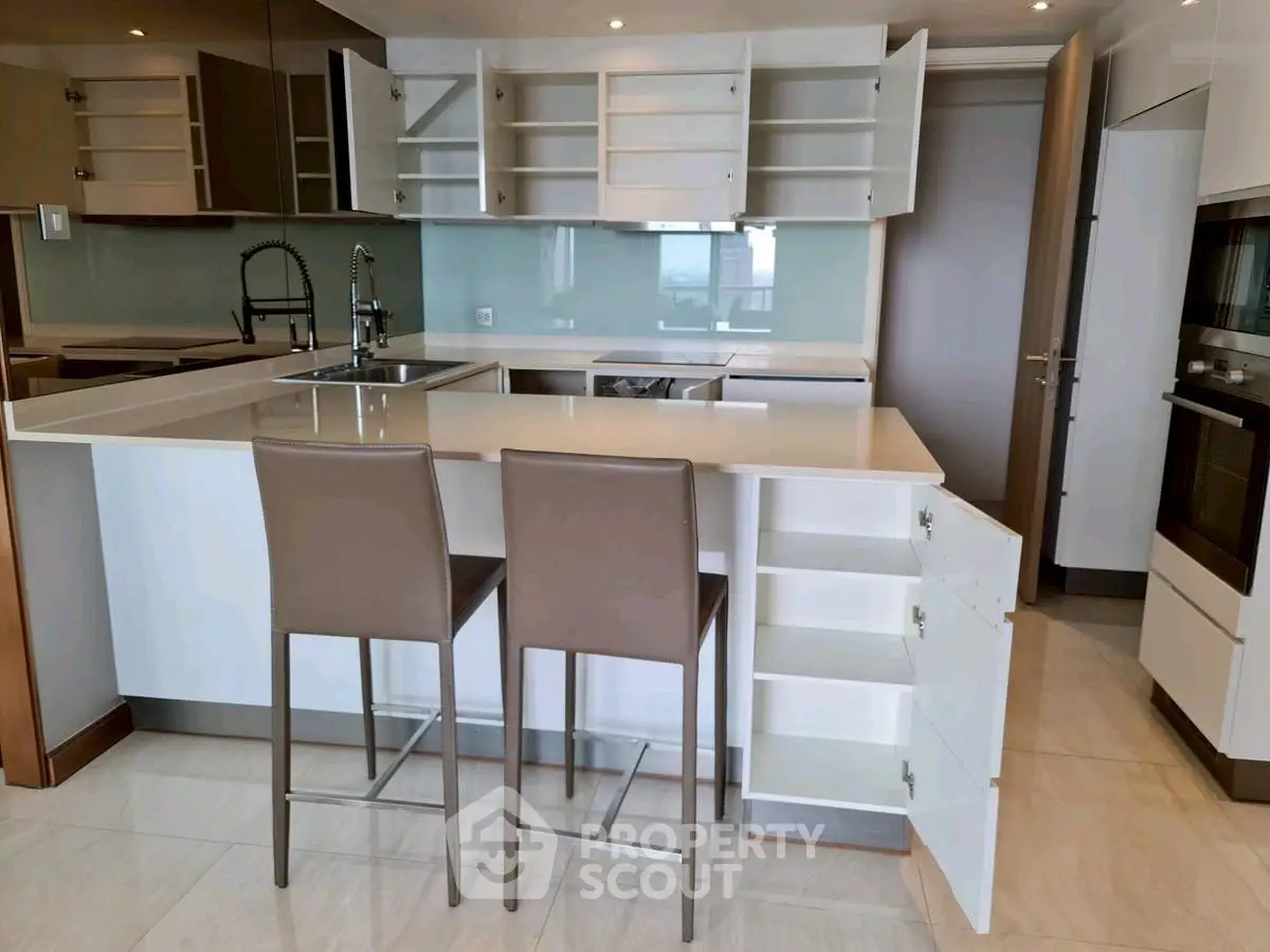 Modern kitchen with open cabinets and sleek bar stools in a stylish apartment.