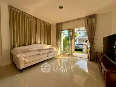 Spacious living room with elegant sofa and large window offering garden view