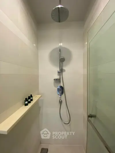 Modern shower area with sleek fixtures and glass door in a contemporary bathroom.