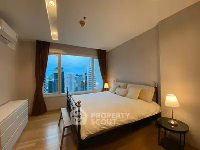 Spacious bedroom with city view and modern furnishings in a high-rise apartment.