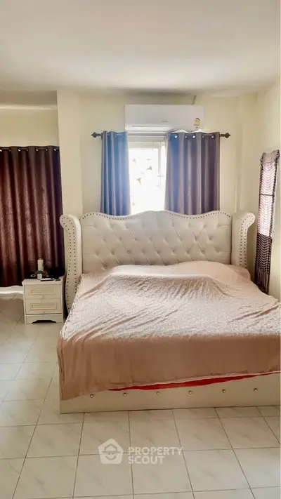 Spacious bedroom with elegant bed and natural light, perfect for relaxation.
