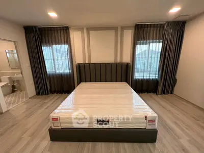 Spacious modern bedroom with large windows and elegant curtains