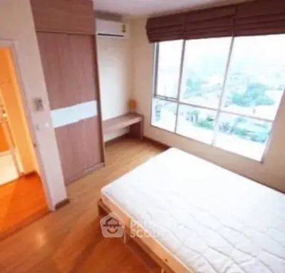 Bright bedroom with large window and wooden flooring