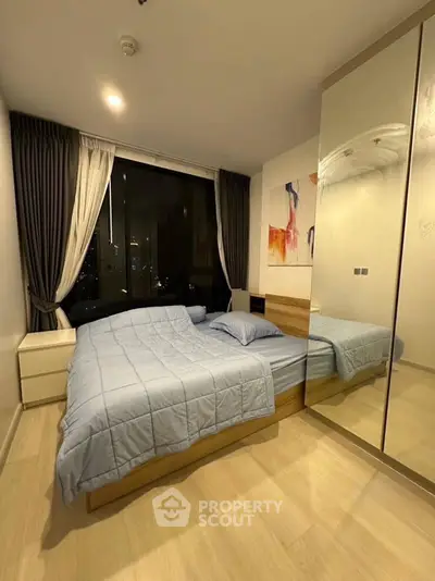 Modern bedroom with large mirrored wardrobe and city view window.