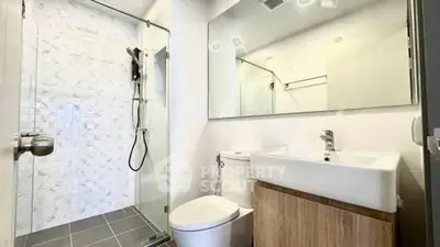 Modern bathroom with sleek shower and stylish vanity in contemporary apartment.