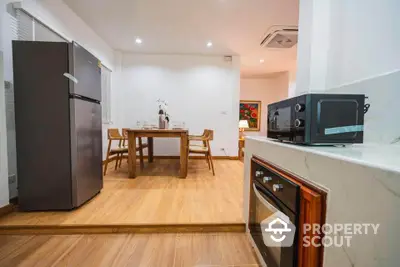 Modern kitchen with sleek appliances and dining area, featuring a stylish open layout and wooden flooring.