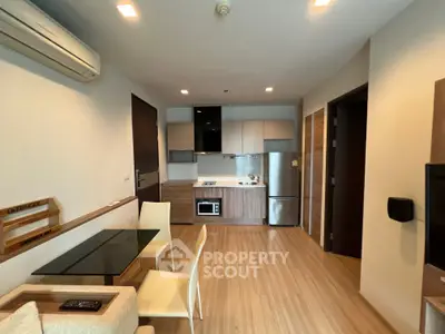 Modern open-layout kitchen and dining area with sleek appliances and wooden flooring.