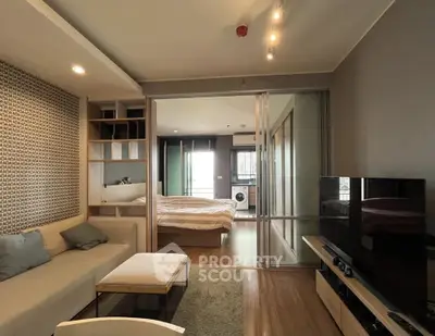 Modern open-plan living room with cozy seating and bedroom view, featuring stylish decor and natural light.