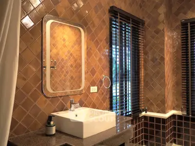 Elegant bathroom with brown tiled walls and modern sink, featuring natural light through window blinds.