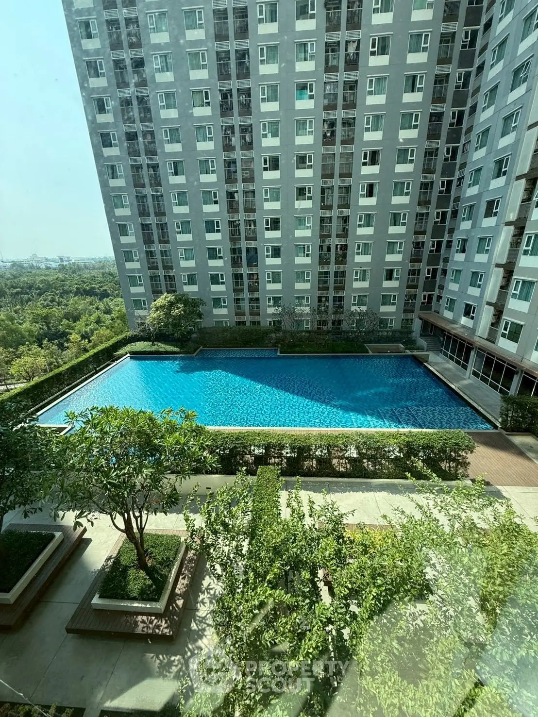Stunning high-rise building with a large pool and lush greenery, offering a serene urban oasis.