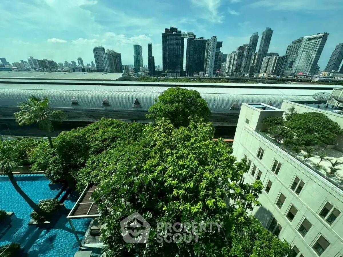 Stunning cityscape view from a high-rise building with lush greenery and pool area.