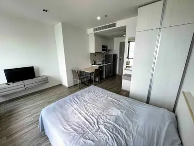 Modern studio apartment with sleek kitchen and cozy bedroom area, perfect for urban living.