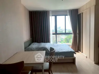 Cozy bedroom with large window and city view, featuring modern furnishings and natural light.