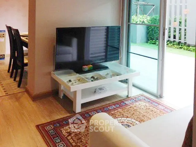 Modern living room with TV and sliding glass doors to a garden patio.