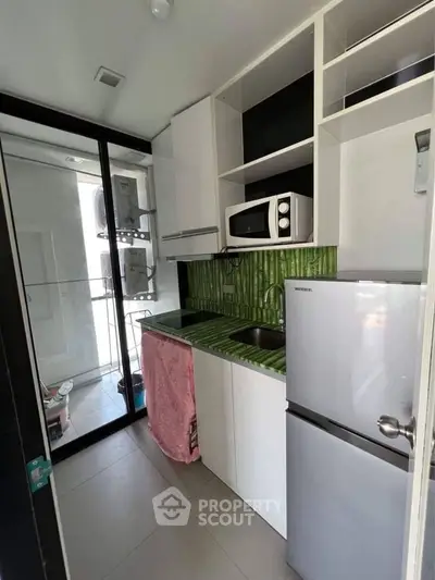 Modern compact kitchen with green backsplash and stainless steel appliances